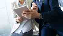 Two professionals reviewing documents on a tablet during a business consultation